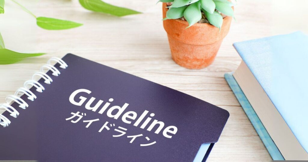 ガイドラインと書かれたノートと観葉植物、本の置かれた机