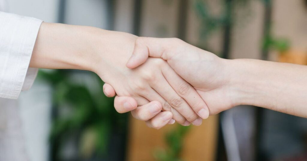 役割分担の合意を象徴する握手の様子